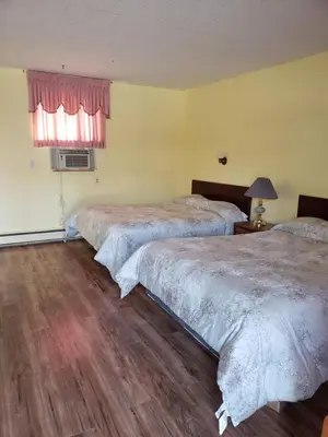 a hotel room with three beds and a window at Olympia Motel in Niagara Falls