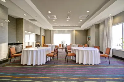 a conference room with tables and chairs and a kitchen at Fairfield Inn & Suites by Marriott Guelph in Guelph