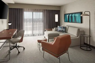 a hotel room with a couch and a table and chairs at Courtyard by Marriott Mississauga-Airport Corporate Centre West in Mississauga