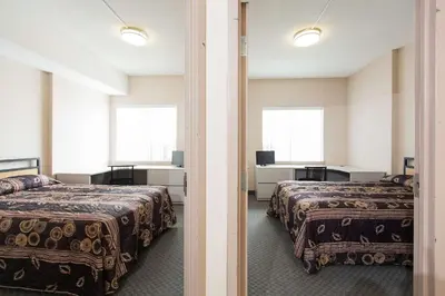 a hotel room with two beds and two windows at Residence & Conference Centre - Kitchener-Waterloo in Kitchener