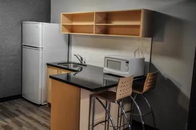 a small kitchen with a microwave and a refrigerator at Residence & Conference Centre - Kitchener-Waterloo in Kitchener