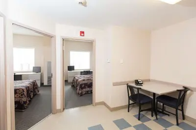 a room with a table and a bed and a mirror at Residence & Conference Centre - Kitchener-Waterloo in Kitchener