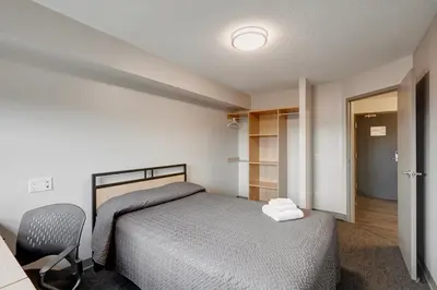 a small bedroom with a bed and a chair at Residence & Conference Centre - Toronto in Toronto