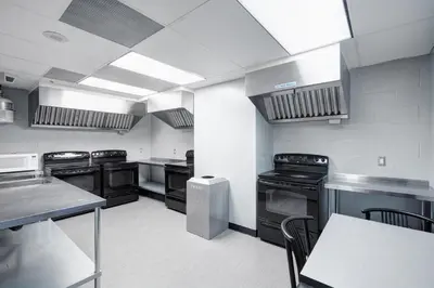 a large kitchen with black appliances and a table at Residence & Conference Centre - Toronto in Toronto