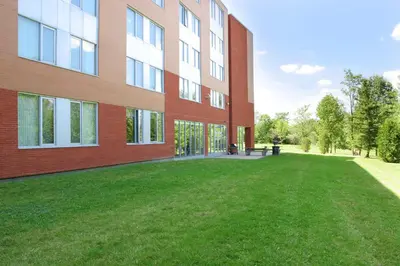 a building with a grass yard in front of it at Residence & Conference Centre - Brampton in Brampton