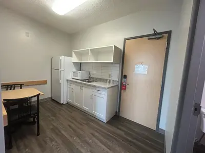 a small kitchen with a table and a refrigerator at Residence & Conference Centre - Brampton in Brampton
