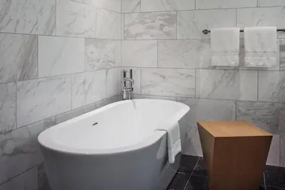 a white bath tub in a bathroom with white tiles at Toronto Marriott Markham in Markham