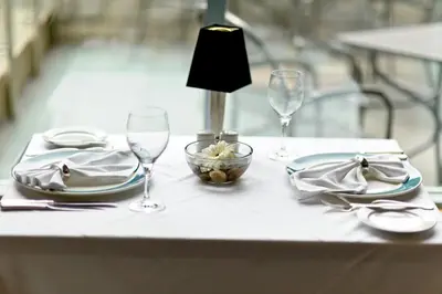a table with plates and glasses and a lamp at The Waterside Inn in Mississauga