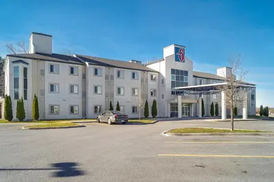 a large white building with a car parked in a parking lot at Motel 6-Peterborough, ON in Peterborough