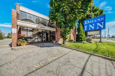 a building with a blue inn sign in front of it at Deluxe Inn in Toronto