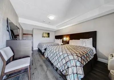 a hotel room with two beds and a chair at Deluxe Inn in Toronto