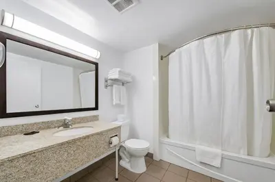 a bathroom with a sink and a toilet and a mirror at Deluxe Inn in Toronto
