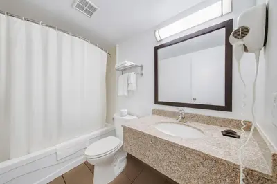 a bathroom with a sink and a toilet and a mirror at Deluxe Inn in Toronto