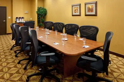 a conference room with a long wooden table and black chairs at Holiday Inn Express Hotel & Suites Clarington - Bowmanville by IHG in Bowmanville