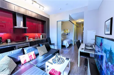 a living room with a blue couch and a kitchen at Upscale Suite at CN Tower, Metro Convention & Rogers Centre in Toronto