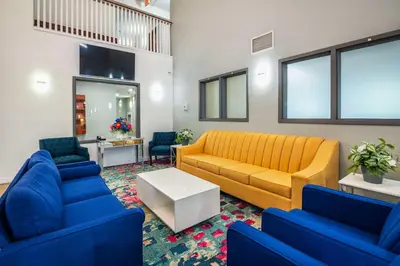 a living room with a yellow couch and blue chairs at Quality Inn & Suites in Grimsby