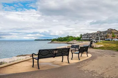 two benches sitting on a sidewalk near the water at Quality Inn & Suites in Grimsby