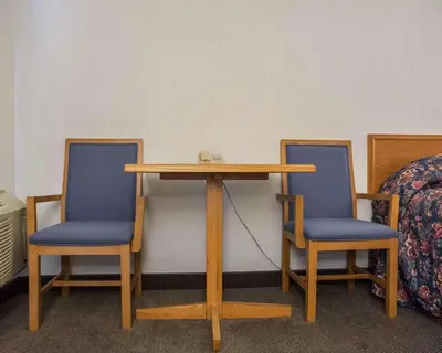 a table with two blue chairs and a table with at Econo Lodge By the Falls in Niagara Falls