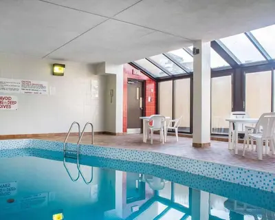 a swimming pool with chairs and tables in a building at Econo Lodge By the Falls in Niagara Falls