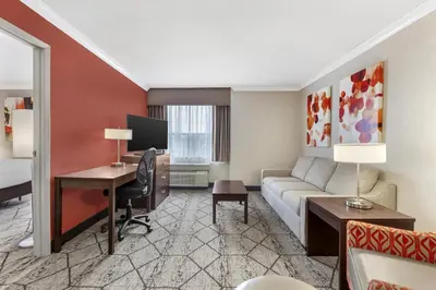 a hotel room with a couch and a desk at Best Western Plus Rose City Suites in Welland