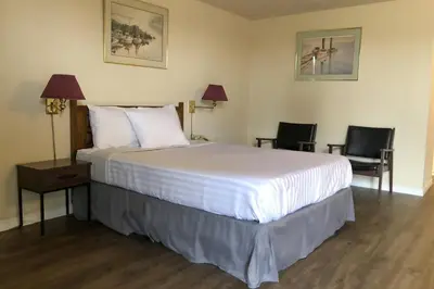 a bedroom with a large bed and two chairs at Knights Inn Fort Erie in Fort Erie