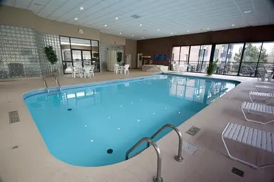 a large pool in a hotel with chairs and tables at Visitor's Inn in Hamilton