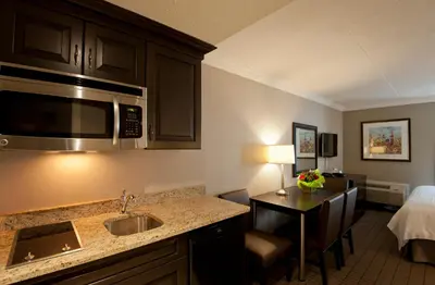 a hotel room with a kitchen with a sink and a bed at Visitor's Inn in Hamilton