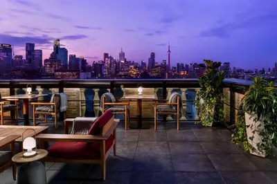 a rooftop patio with tables and chairs and a city skyline at Park Hyatt Toronto in Toronto