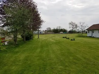a large grass field with a house and a tree at Eastwood Motel in Woodstock