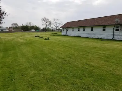 a large grass field next to a white barn at Eastwood Motel in Woodstock