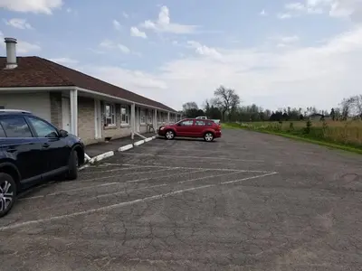 a red car parked in a parking lot next to a building at Eastwood Motel in Woodstock