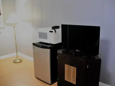 a microwave sitting on top of a stand next to a refrigerator at Eastwood Motel in Woodstock