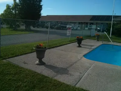 a swimming pool with two flower pots next to a fence at Port Motel in Port Colborne