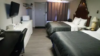 a hotel room with two beds and a television at Port Motel in Port Colborne