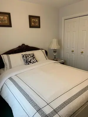 a bedroom with a large white bed and a lamp at Susan's Villa in Niagara Falls