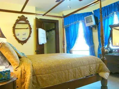a bedroom with a bed with blue curtains and a mirror at A Night to Remember B & B in Niagara Falls