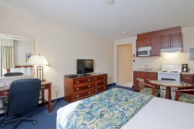 a hotel room with a bed and a desk and a kitchen at Travelodge by Wyndham Trenton in Trenton