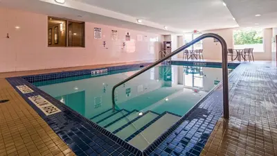 a swimming pool with a blue tiled floor and a swimming pooliteratorhaarhaar at Best Western Plus Bowmanville in Bowmanville