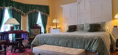 a bedroom with a bed with a green comforter at A Moment in Time Bed and Breakfast in Niagara Falls