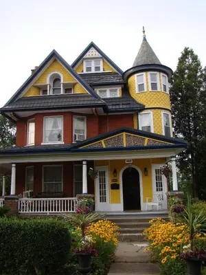 a yellow and orange house with a turret at A Moment in Time Bed and Breakfast in Niagara Falls