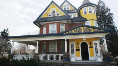 a large yellow and red house with a turret at A Moment in Time Bed and Breakfast in Niagara Falls