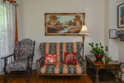 a living room with a chair and a painting on the wall at Niagara Inn Bed and Breakfast in Niagara Falls