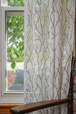 a window with a curtain and a wooden chair at Niagara Inn Bed and Breakfast in Niagara Falls