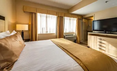 a hotel room with a large bed and a flat screen tv at Monte Carlo Inn & Suites Downtown Markham in Markham