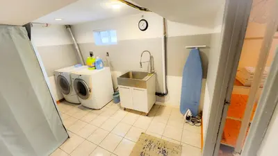 a bathroom with a washing machine and a sink at Richview Gardens Apartment in Toronto