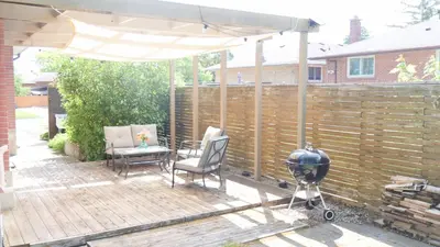 a patio with an umbrella and chairs and a grill at Richview Gardens Apartment in Toronto