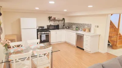 a kitchen with white cabinets and a glass table at Richview Gardens Apartment in Toronto