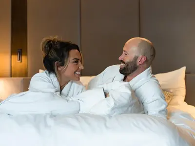 a man and a woman laying in bed at The Hazelton Hotel in Toronto