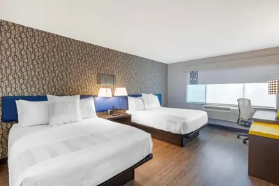 a hotel room with two beds and a desk at GLō Best Western Mississauga Corporate Centre in Mississauga