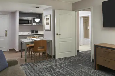 a living room with a table and a kitchen at Homewood Suites by Hilton Toronto Vaughan in Vaughan